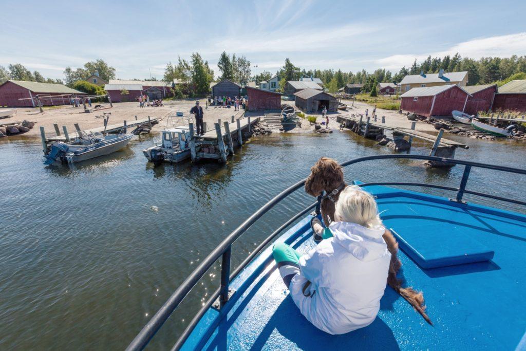 Veneen kannella tyttö ja koira matkalla kohti Tammion kalastajakylää Haminassa.